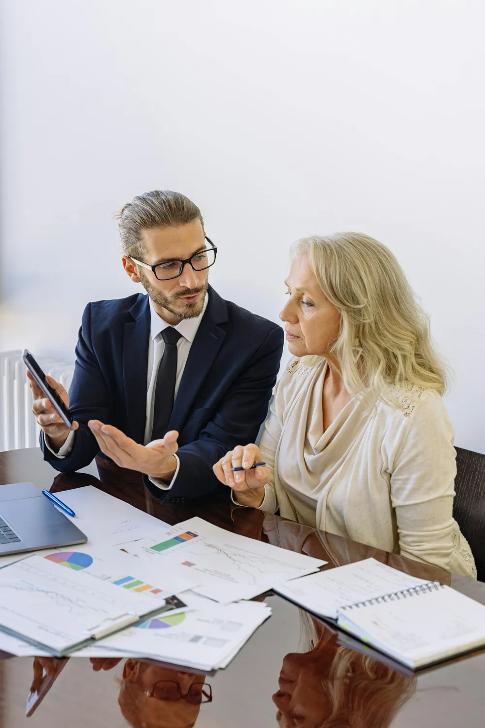 An advisor reviewing printed financial plans with a client across a conference table
